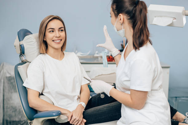 Dentist examining young woman's teeth in clinic.